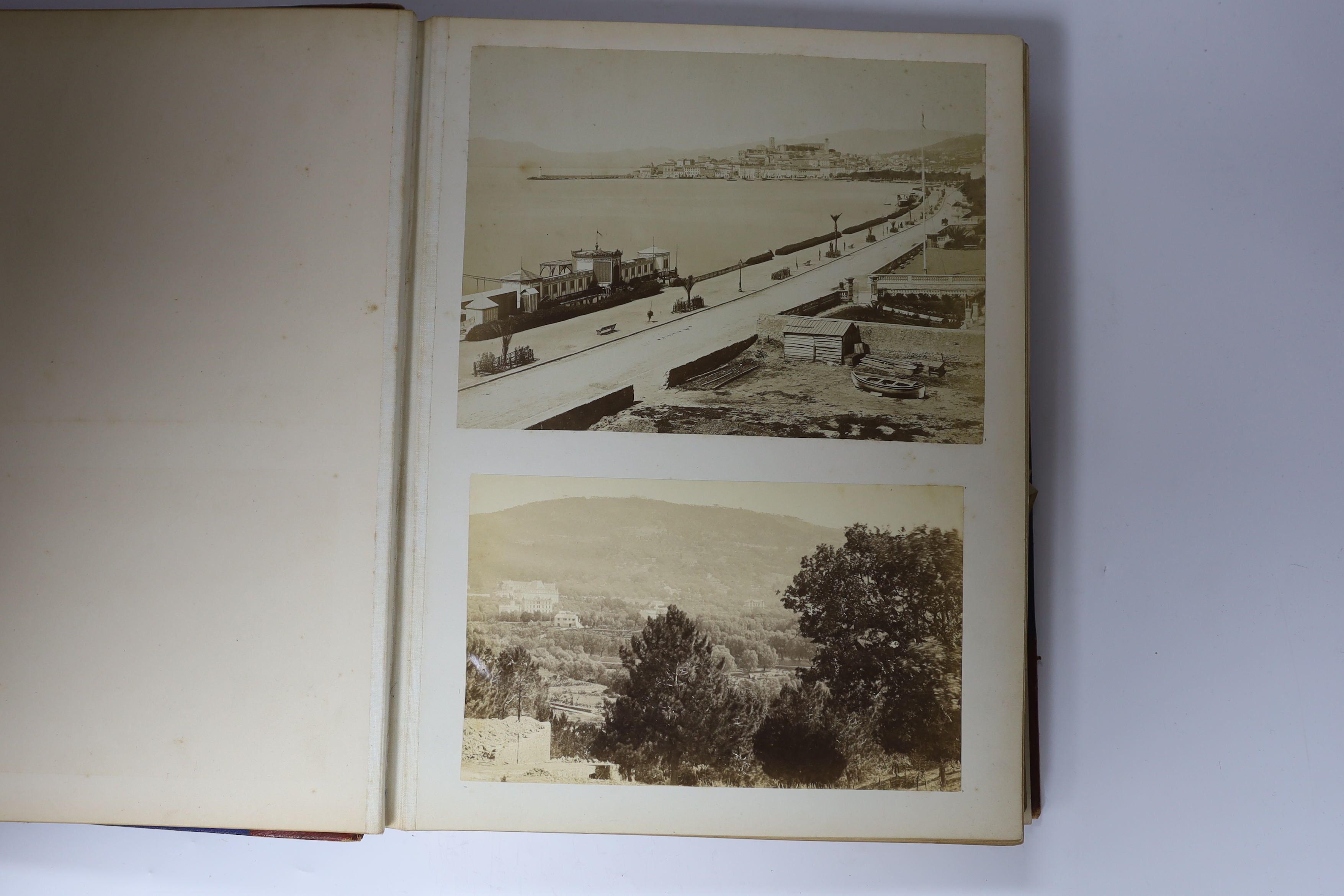 A late 19th century album of black and white photographs of views, principally in Europe and including family groups and portraits, country house interiors et., folio, half red morocco, 37 x 27cms